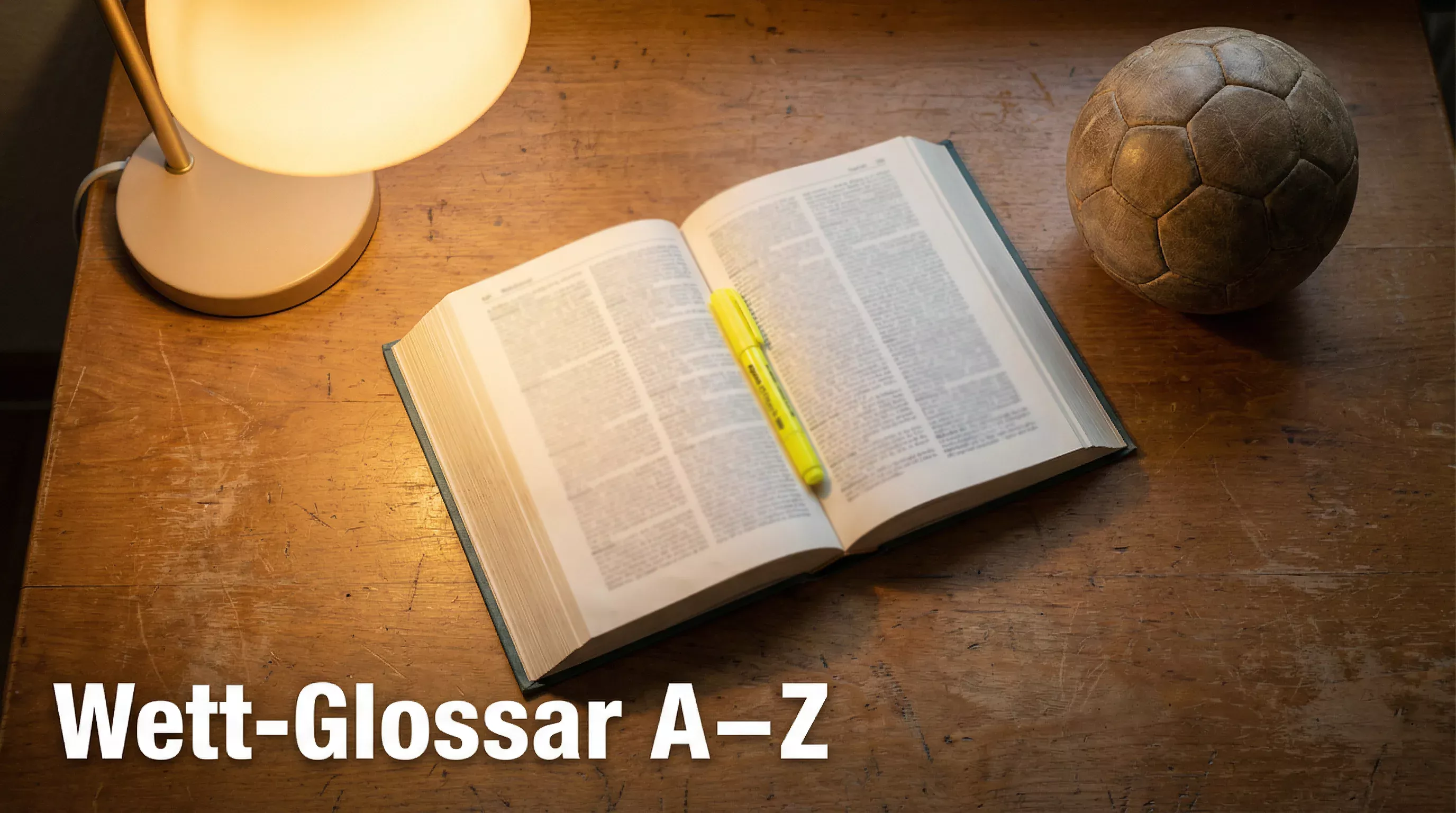Aufgeschlagenes Lexikon mit Handball und Textmarker auf einem Holztisch